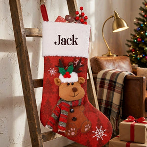 Personalized red Christmas stocking with a plush reindeer on a wooden ladder, lit so the fur cuff and the name read clearly
