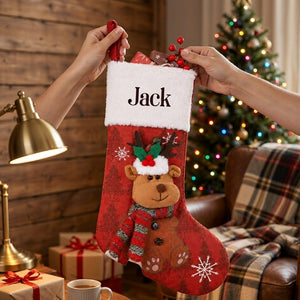 Two hands lifting the personalized red stocking with its plush reindeer up at chest height