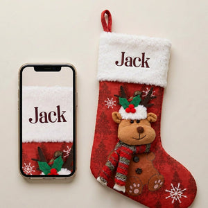 Personalized red stocking with a plush reindeer laid flat beside a phone showing the same name on the same fur cuff