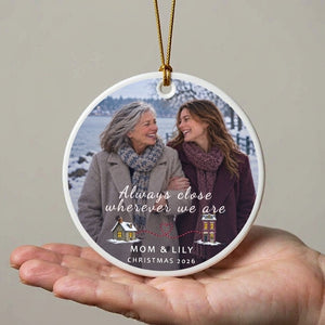Personalized long distance ornament for Mom held above an open adult palm, showing its 5 in scale against a plain wall