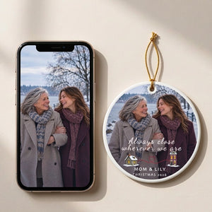 Personalized long distance ornament for Mom beside the phone photo it was made from, both lying on a pale surface